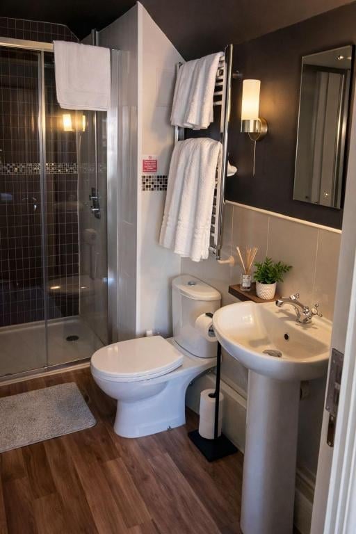 A Union Inn ensuite bathroom with a walk-in shower, pedestal sink and wood-look flooring