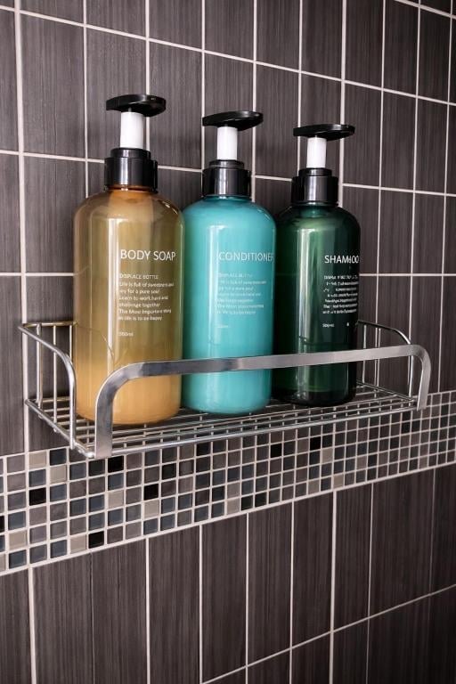 Body soap, conditioner and shampoo in a wire shelf mounted on a tiled Union Inn bathroom wall