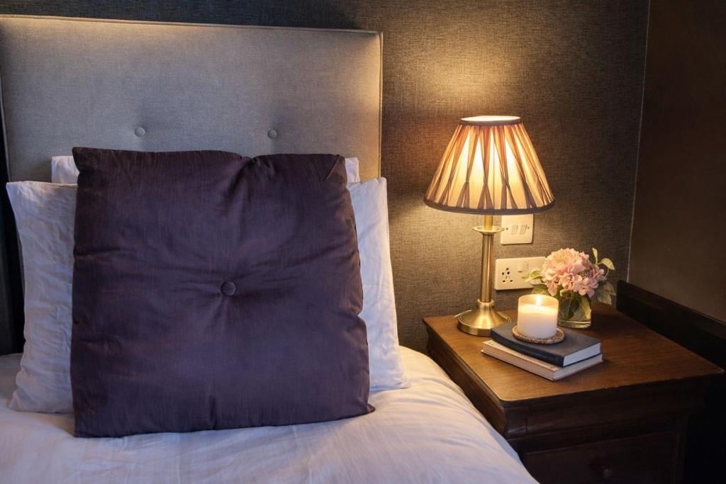 A modern Union Inn bedroom with white bedding, an upholstered headboard and a brass lamp on the nightstand