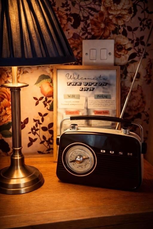 A vintage black Bush radio, brass table lamp and a framed welcome sign in a Union Inn bedroom