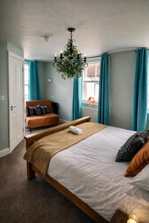 A Union Inn bedroom with a wooden bed, white and orange bedding, turquoise curtains and a hanging plant chandelier