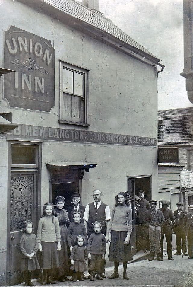 Historic black and white photograph of the licensee, family and regulars standing in front of The Union Inn, showing the painted Union Inn board, B. Mew Langton & Co Osborne Pale Ales & Stout signage, and the Salvate Bar door