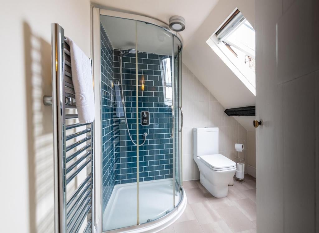 A Union Inn bathroom with a curved glass shower enclosure, blue tile walls and a skylight above