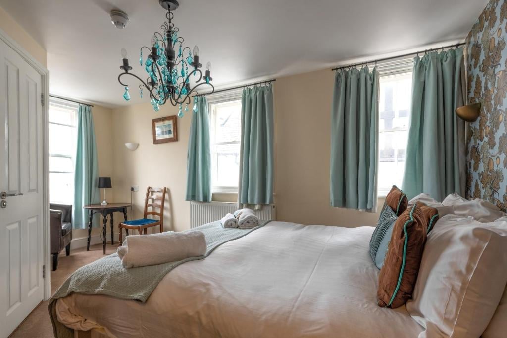 A Union Inn bedroom with a turquoise chandelier, white linen and teal curtains